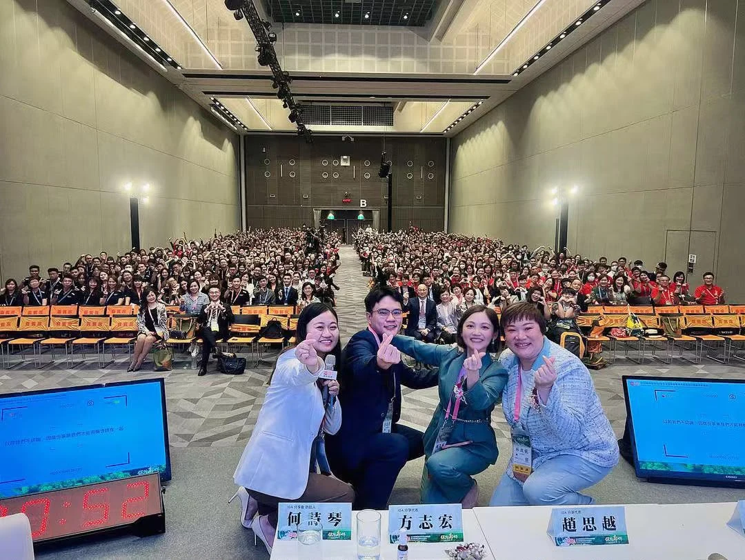 Jessie Chiu with fellow speakers in front of a large professional audience